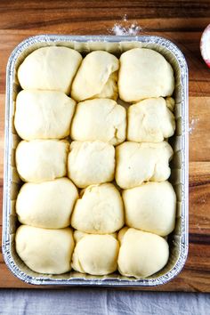 a pan filled with dough sitting on top of a wooden table next to an apple