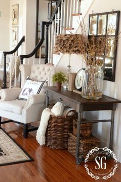 a living room filled with furniture next to a stair case and mirror on the wall