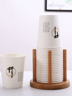 two cups are sitting next to each other on a white table top with a wooden stand