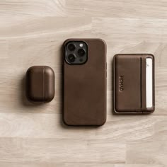 an iphone case sitting on top of a wooden table next to a wallet and earbuds