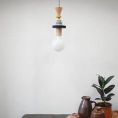 a table topped with vases next to a plant and a light bulb hanging from the ceiling