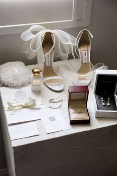 wedding shoes, ring boxes and jewelry are on the table next to eachother