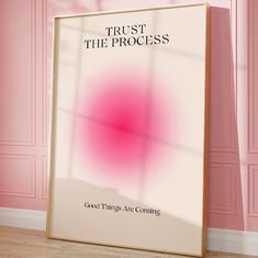 a poster with the words trust the process on it in front of a pink wall