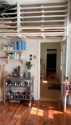 a room with wooden floors and shelves filled with crafting supplies on top of it