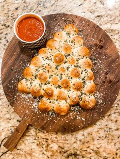 a pizza sitting on top of a wooden cutting board next to a bowl of sauce