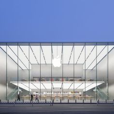 an apple store with people walking in front of it