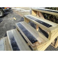 two wooden benches sitting next to each other on top of cement slabs in a parking lot