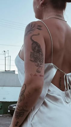 a woman in a white dress with tattoos on her back