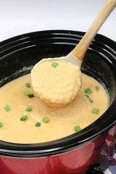 a wooden spoon scooping some food out of a crock pot with broth