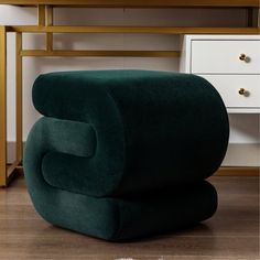 a green chair sitting on top of a wooden floor next to a white dresser and desk