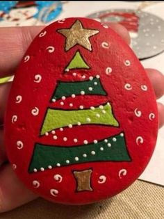 someone is holding a painted rock with a christmas tree on it