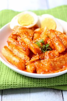 a white plate topped with pasta covered in sauce next to sliced lemons and an egg