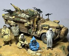 a group of figurines sitting on top of a table next to a toy army vehicle