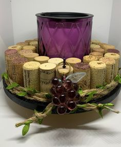 a tray with wine corks and grapes on it, next to a purple candle