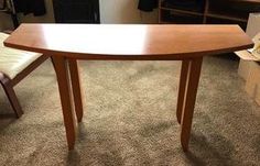 a wooden table sitting on top of a carpeted floor next to a white chair