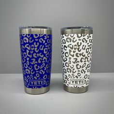 two yeti tumblers sitting next to each other on a white counter top with blue and black leopard print