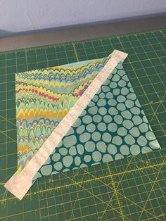 two pieces of fabric sitting on top of a green cutting board next to a ruler