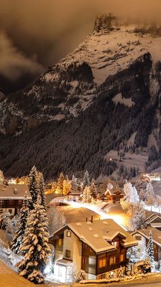 a snow covered mountain with houses in the foreground and trees on the other side