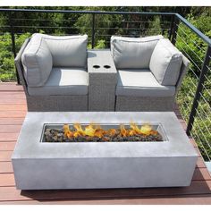 a fire pit sitting on top of a wooden deck next to two couches and a table