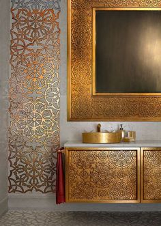 a gold bathroom vanity with a mirror above it and a red towel hanging on the wall