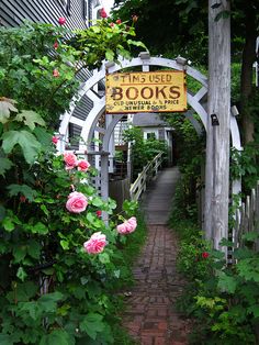 a sign that reads this used books is in the middle of a garden with pink flowers