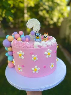 a pink cake with white frosting and colorful decorations