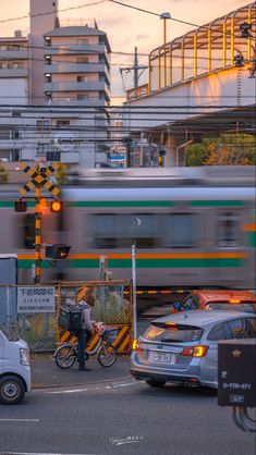 a blurry image of a train passing by some cars and people crossing the street