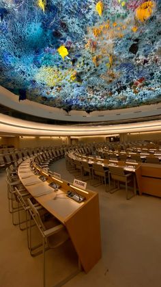 a large room with many tables and chairs in front of a ceiling that looks like corals