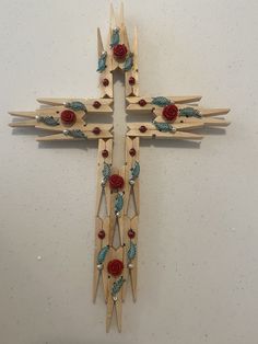 a cross made out of wooden sticks with red roses on the top and green leaves