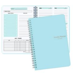 a spiral bound planner with a blue cover and lined pages on the front, sitting next to an empty notebook