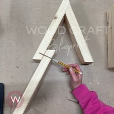 a person is making a triangle out of wood and glues it with a pencil