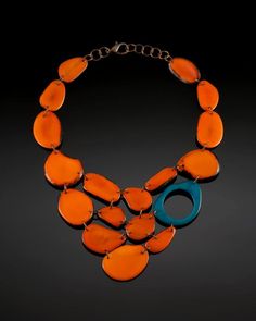 an orange and blue necklace is displayed on a black background with a circular link around it