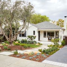 a white house with trees and plants in the front yard