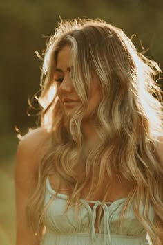 a woman with long blonde hair standing in a field