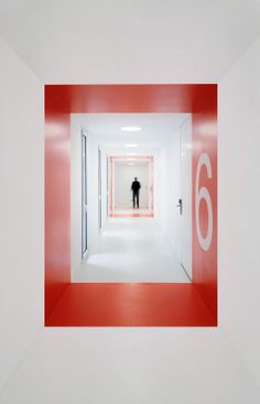 a black and white photo of a man standing in the middle of an empty hallway