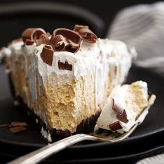 a piece of cake with white frosting and chocolate toppings on a black plate