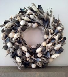 a wreath made out of seashells and driftwood is displayed on a shelf