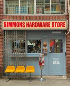 two yellow chairs sitting in front of a storefront with the words simon's hardware store on it