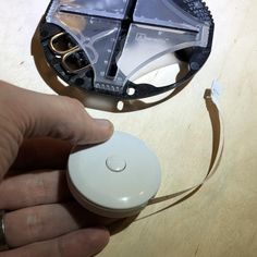 a hand is holding a mouse on top of a wooden table next to a piece of plastic