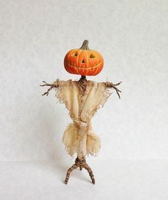 an orange pumpkin sitting on top of a scarecrow's head with arms and legs