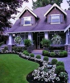 a house with landscaping in front of it and lots of flowers on the lawn outside