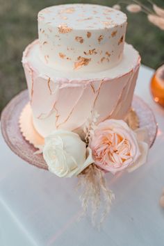 a three tiered wedding cake with pink and gold frosting on a glass plate