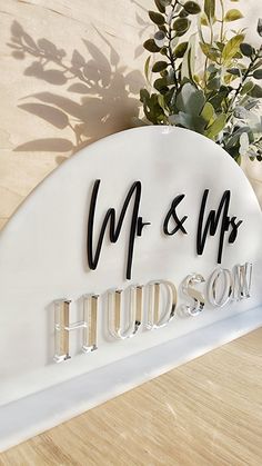 a white sign that says mr and mrs hudson with flowers in the corner behind it