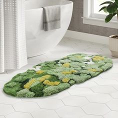 a bathroom rug with flowers on it in front of a bathtub and toilet paper