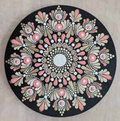 a black plate with pink and white designs on it's side, sitting on a table