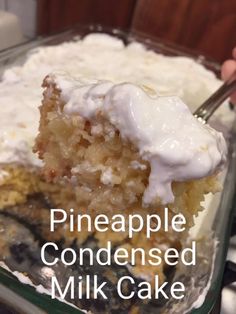 a piece of pineapple cake with white frosting on top is being lifted from a casserole dish