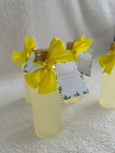 three small bottles with yellow bows on them sitting on a white cloth covered tablecloth