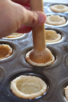 a person holding a wooden spoon in a muffin tin