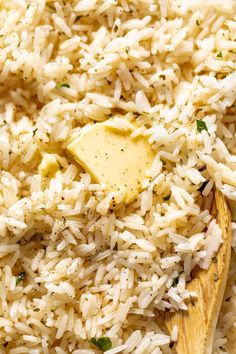 a wooden spoon filled with rice and parmesan on top of a white plate