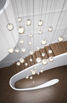 an overhead view of a spiral staircase with lights hanging from the ceiling and wood flooring